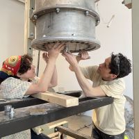 Rörstrand Museum. Anton Alvarez, Under Pressure, the inagural exhibition. Anton assisted by Blanche Vivet fits one of the moulds to the gigantic Extruder, purpose-built by Anton, a machine through which stoneware claybody is formed into extraordinary shapes inside the gallery. The performance part of the exhibition. WIP snap. 2022.